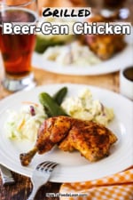 A white dinner plate filled with a beer can chicken let quarter and coleslaw, pickles, and potato salad.