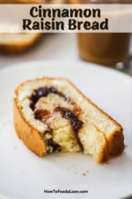 A slice of cinnamon raisin bread with a bite taken out of it sitting on a small white plate next to a mug of coffee.