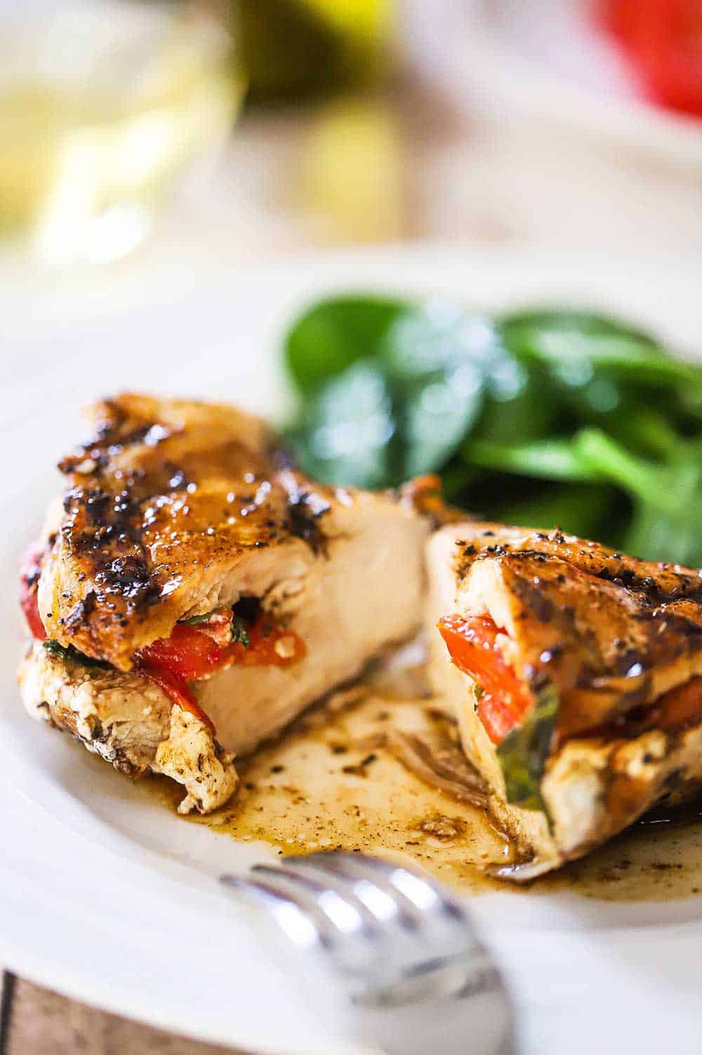 A chicken breast that has been sliced in half to reveal that is has been stuffed with tomatoes, mozzarella cheese, and fresh basil. 