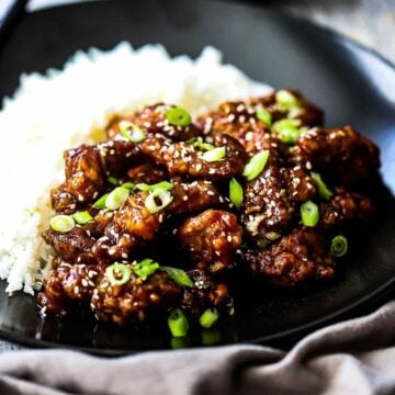 A plate filled with sesame beef and steamed white rice.