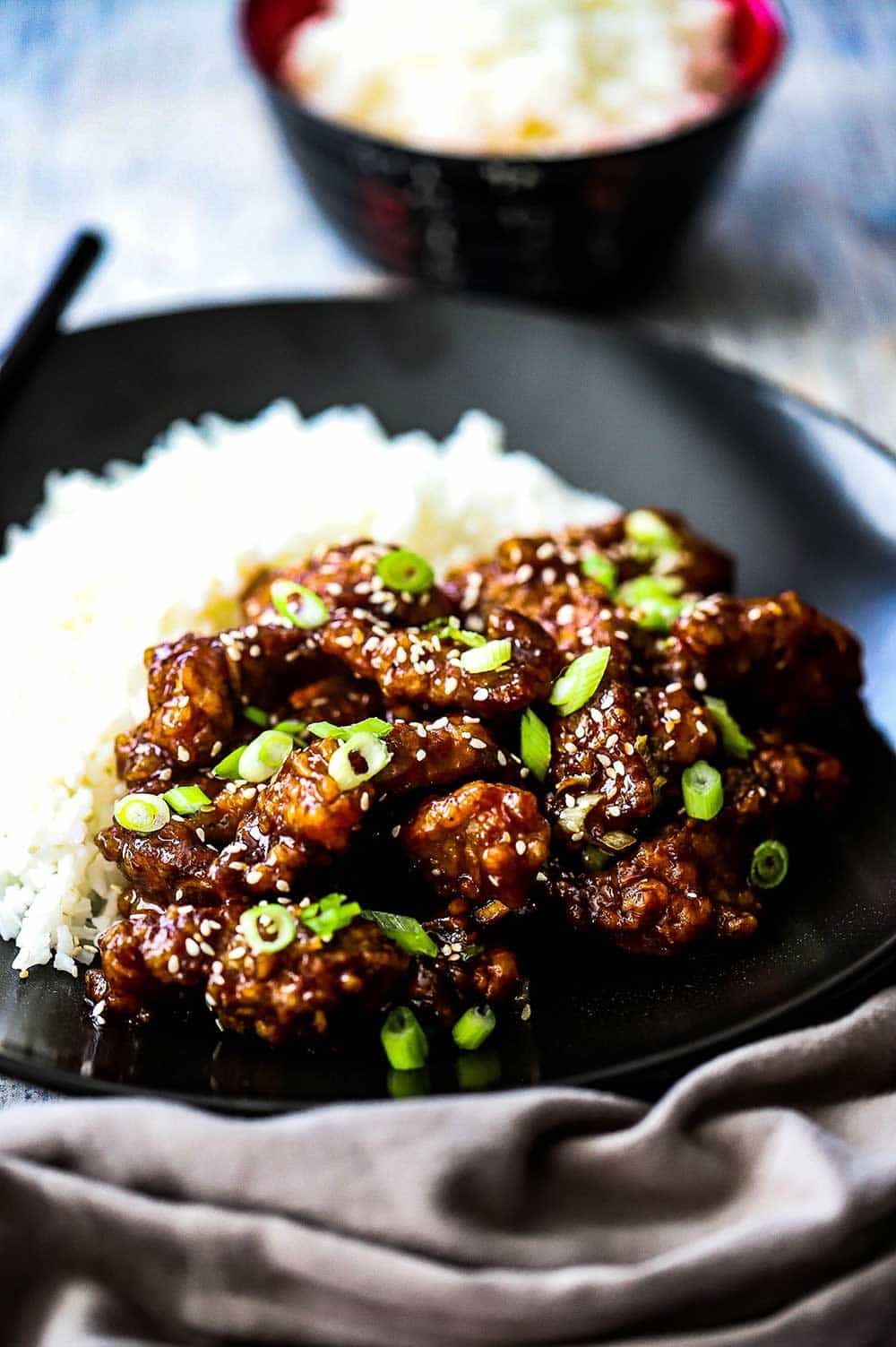 A plate filled with sesame beef and steamed white rice.