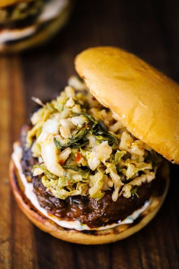 An overhead view of a bulgogi burger that is topped with easy kimchi all on a toasted brioche bun. 