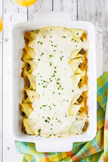 Baked savory crêpes in a 9 by 13 baking dish topped with a mornay sauce and snipped chives.