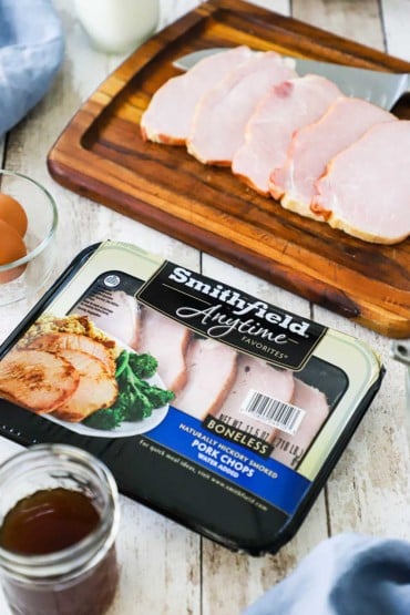 An overhead view of a package of Smithfield boneless smoked pork chops sitting next to a cutting board of the pork chops out of the package.