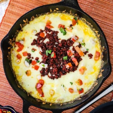 An overhead view of a cast-iron skillet filled with queso fundido.
