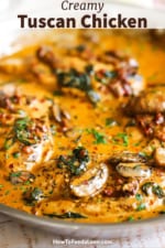 A close-up view of a skillet filled with creamy Tuscan chicken with mushrooms and spinach.