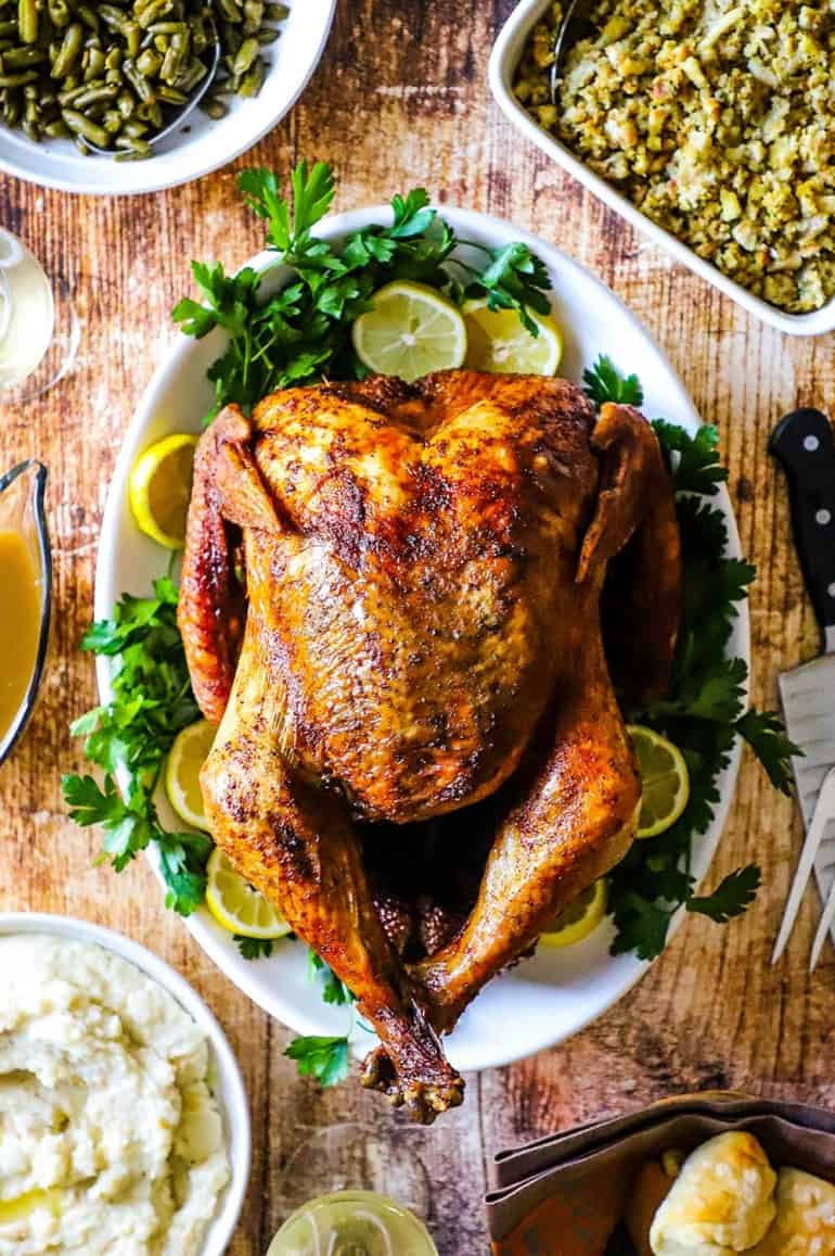 An overhead view of a deep-fried turkey sitting on a platter surrounds by other holiday side dishes.