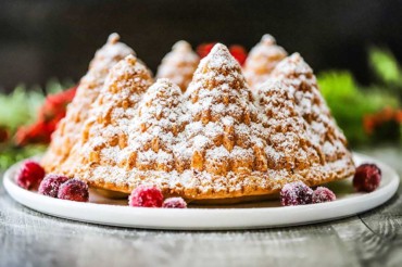 A straight-on view of a Christmas bundt cake that has been sprinkled all over with powdered sugar.
