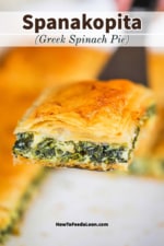 A square piece of freshly baked spanakopita being held up on a large silver spatula.