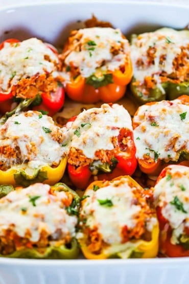 Three rows of turkey and rice stuffed bell peppers in a white baking dish.