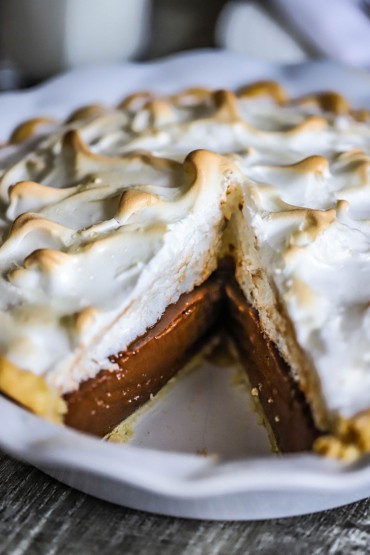 A close-up view of a homemade chocolate meringue pie with a slice missing from it.