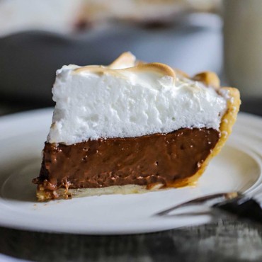 A close-up view of a slice of chocolate meringue pie on a dessert plate.