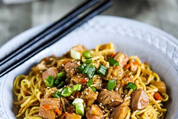 Two bowls filled with slow-cooker chicken chow mein with the bowl in the forefront holding two chopsticks on the side.