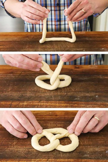 A person holding up two ends of a rope of pretzel dough and then that person twisting the ends together and then finally the person forming the dough into a pretzel.