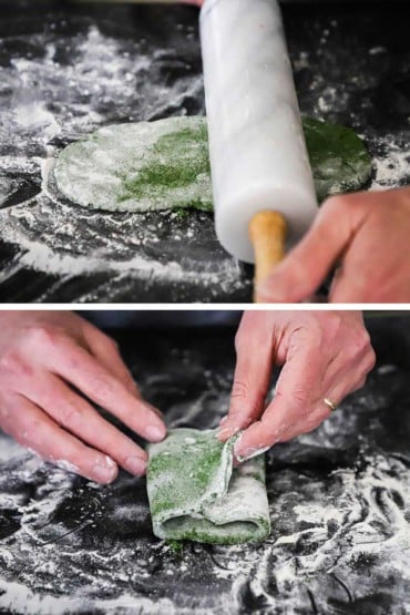 A person using a ceramic rolling pin to flatten spinach pasta and then that person folding over the ends of the pasta sheet.