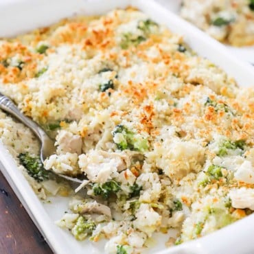 A close-up view of a 9 by 13 baking dish filled with a chicken and rice casserole with broccoli and cheese.