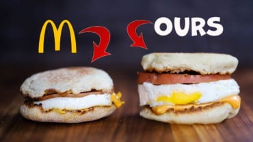 A McDonald's Egg McMuffin sitting on a wooden cutting board next to a homemade Egg McMuffin on the other side.