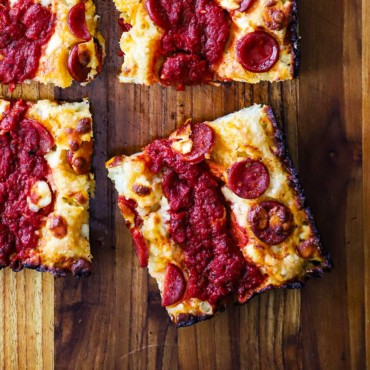 An overhead view of a Red Stripe Detroit-Style Pizza that has been cut into four squares.