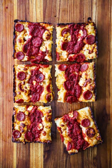 An overhead view of a deep-dish pepperoni pizza that has been cut into six squares.
