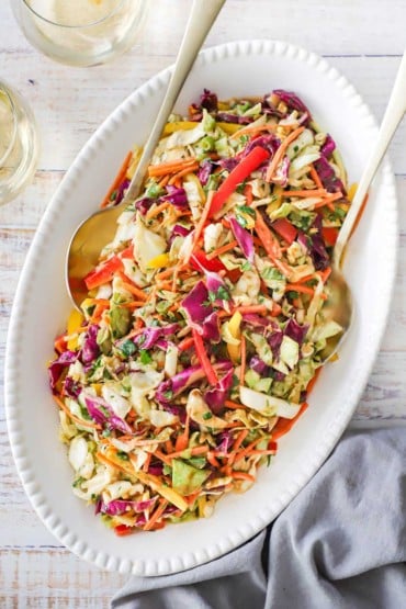 An overhead view of an oval white platter filled with an Asian slaw with Peanut Ginger Dressing.