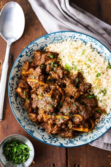 An overhead view of Thai beef in a colorful bowl with the beef on one side and Jasmine rice on the other side.