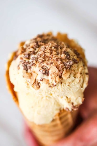 An overhead view of an ice cream waffle cone that is filled with salted caramel ice cream and topped with toffee bits.