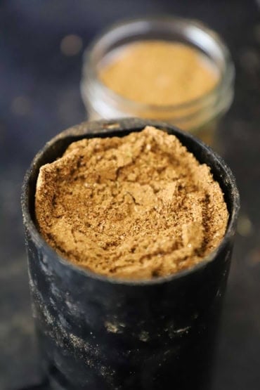 A close-up view of a spice grinder that is filled with freshly ground garam masala.