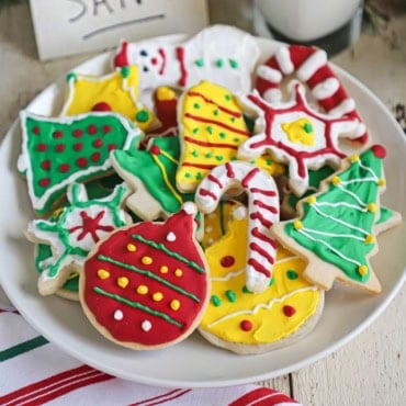 A straight-on view of a white plate filled with a collection of colorful homemade Christmas cookies.