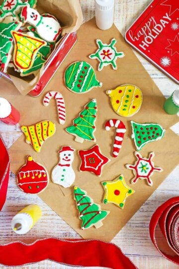 An overhead view of a collection of colorful homemade Christmas cookies that in the shape of bells, ornaments, tress, snowmen, and bells.