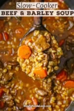 An overhead view of a wooden ladle lifting up a helping of beef and barley soup form a slow cooker filled with the same.