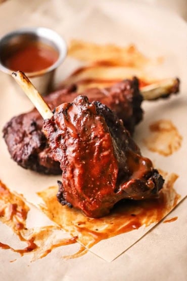 A straight-on view of two pork wings stacked against each other and each have been smoked and then slathered with barbecue sauce.