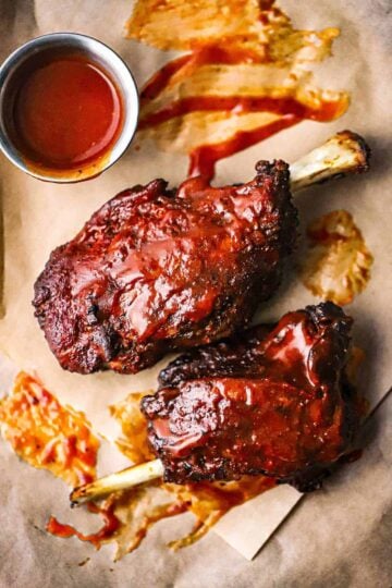 An overhead view of two smoked pork wings that are fully cooked and slathered with homemade barbecue sauce.