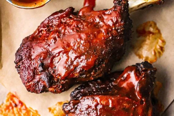 An overhead view of two smoked pork wings that are fully cooked and slathered with homemade barbecue sauce.