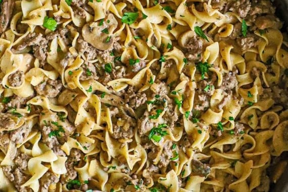 An overhead view of a large straight-edge stainless steel skillet filled with weeknight stroganoff of a creamy ground beef sauce tossed with egg noodles.