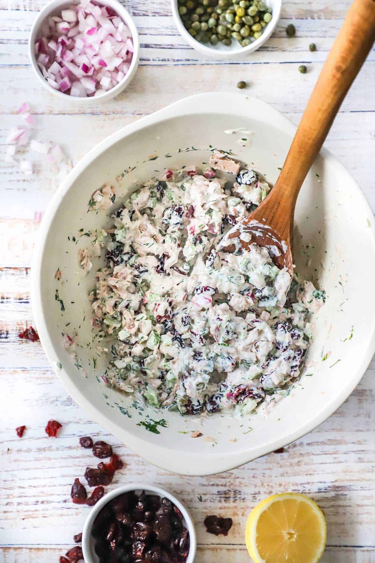 A ceramic bowl filled with best-ever tuna salad with a wooden spoon inserted off to the side. 