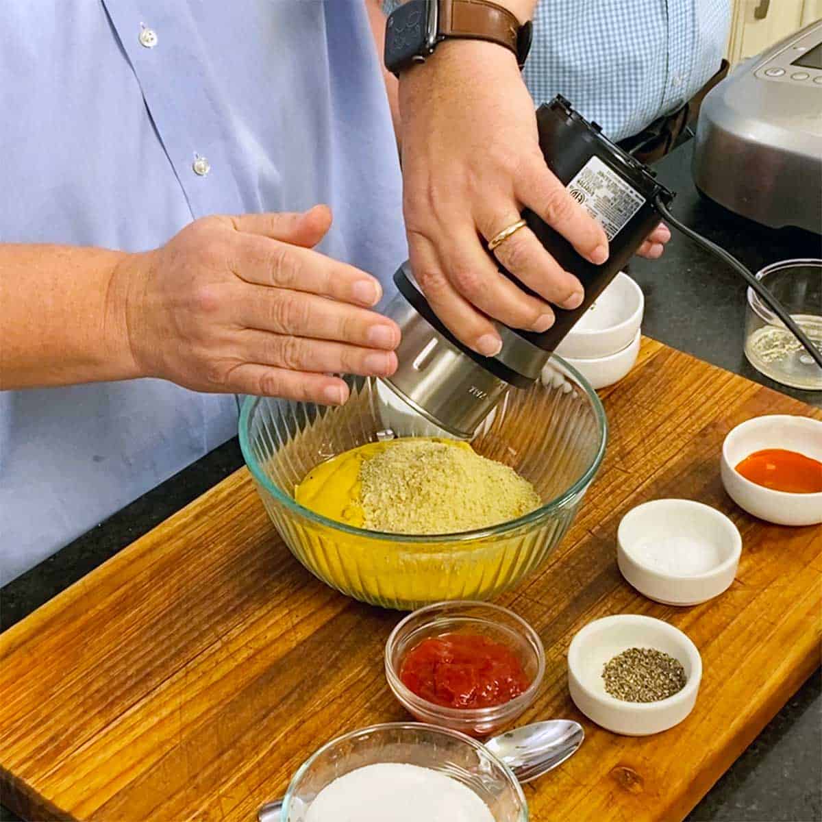 A person dumping ground spices from a spice grinder into a glass bowl on a cutting board. 