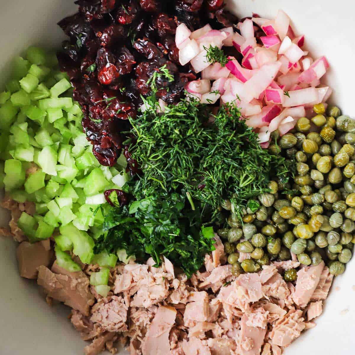 A bowl of un-mixed ingredients for a gourmet tuna salad. 