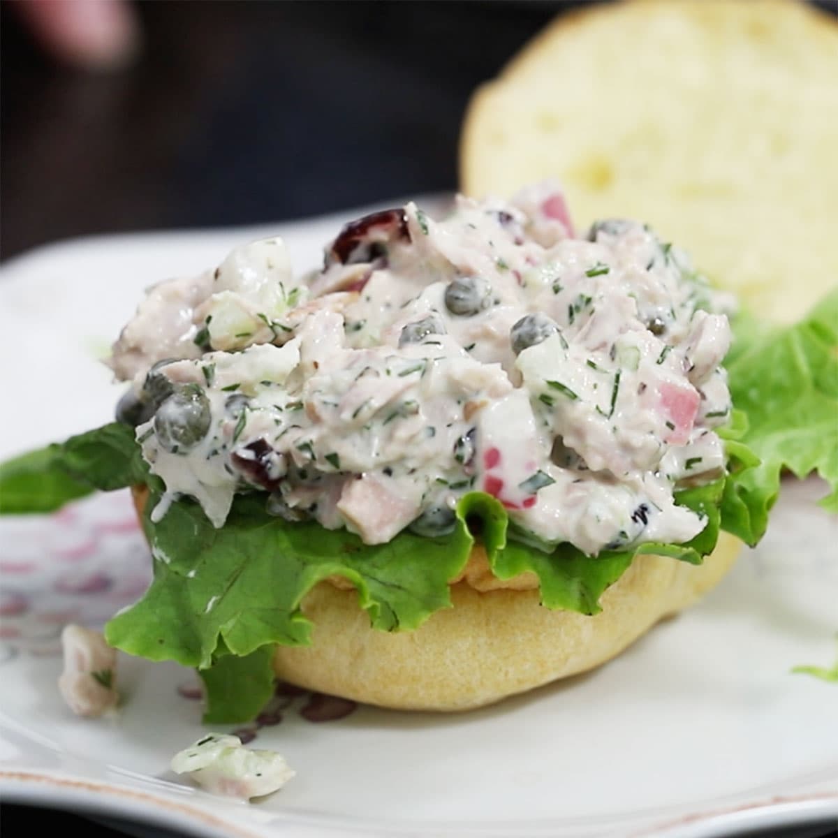 A small sandwich slider of best-ever tuna salad resting on a layer of green leaf lettuce. 