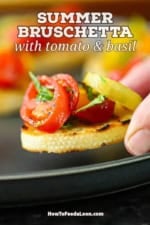 A person placing a Summer bruschetta with tomato and basil on a black plate next to more burshetta.