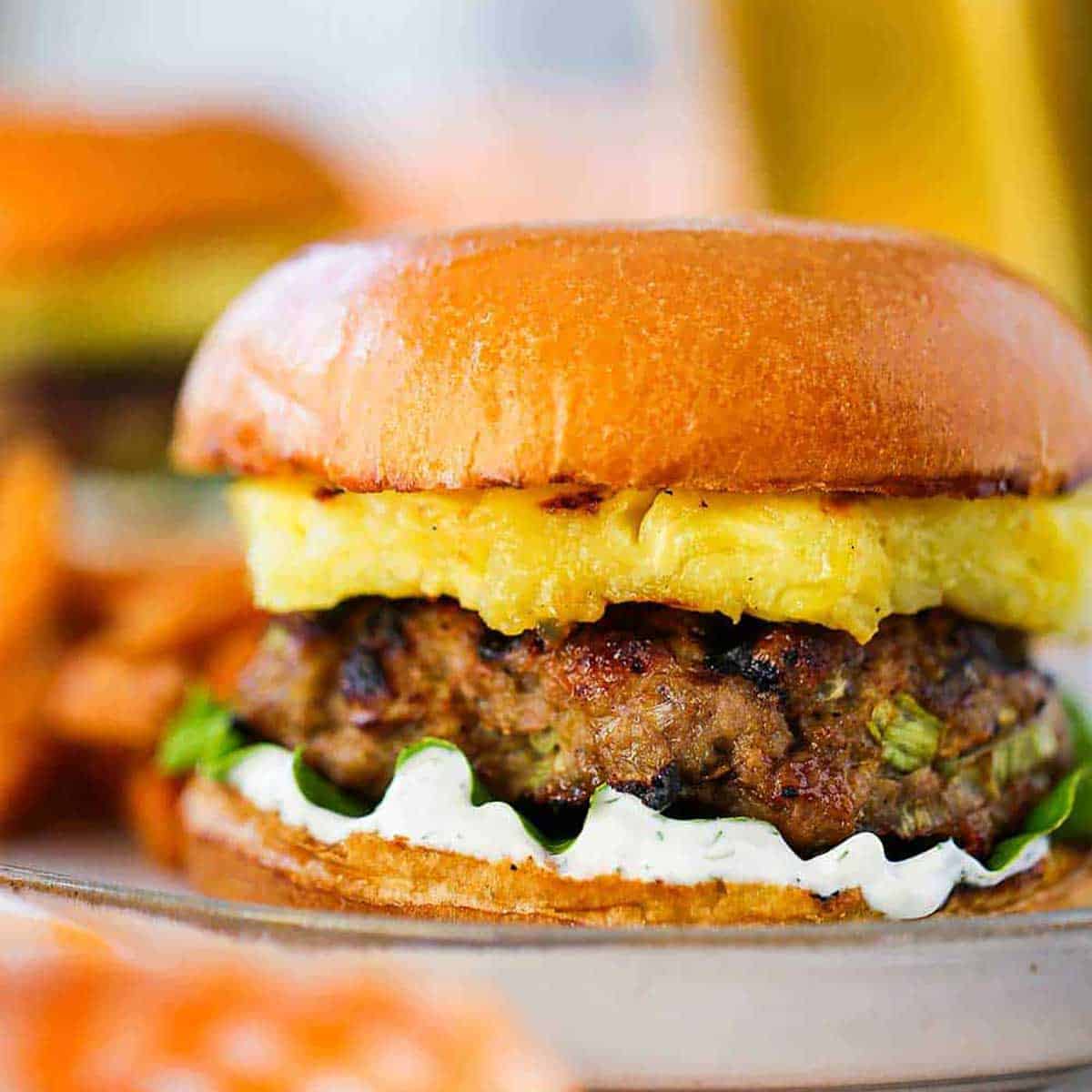 A curry turkey butter with grilled pineapple sitting a plate and is garnished with a dill yogurt sauce and green leaf lettuce.