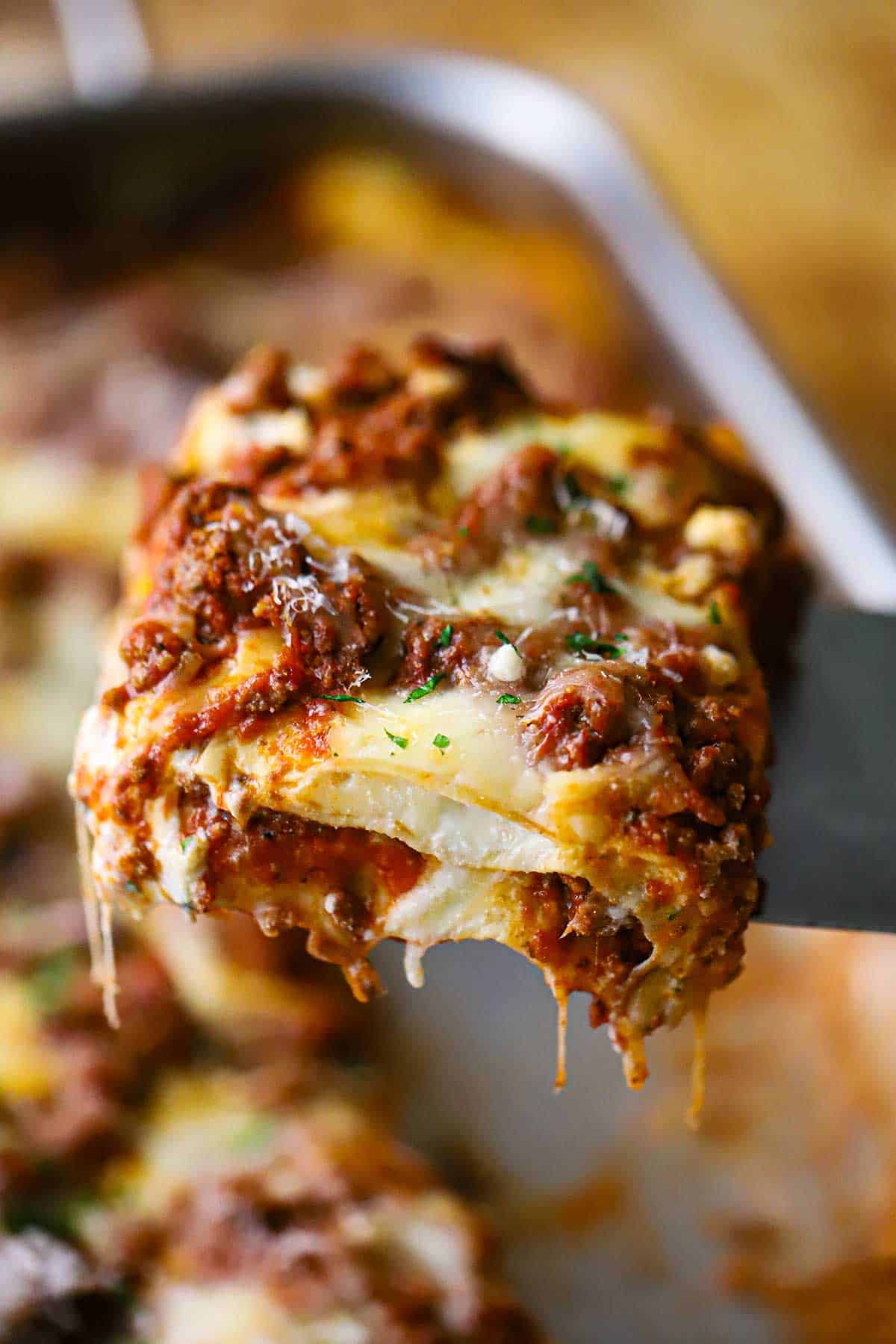 A metal spatula being used to raise a slice of the best weeknight lasagna up from a pan of the same.