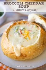 A close-up view of a sourdough bread bowl filled with broccoli cheddar soup.