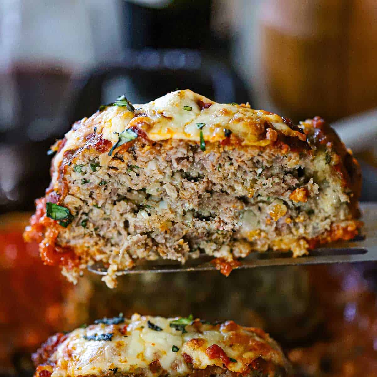 A metal spatula being used to lift up a slice of The Best Juicy Italian Meatloaf with Marinara Glaze.