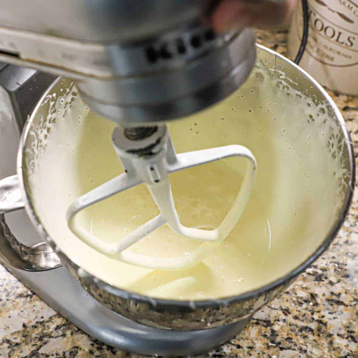A view into the bowl of a stand mixer that is filled with eggs that have been vigorously whipped with sugar and are not pale and fluffy.
