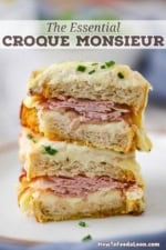 Two Croque Monsieur sandwiches that have both been split in half and stacked, revealing the ham and melty cheese interior.