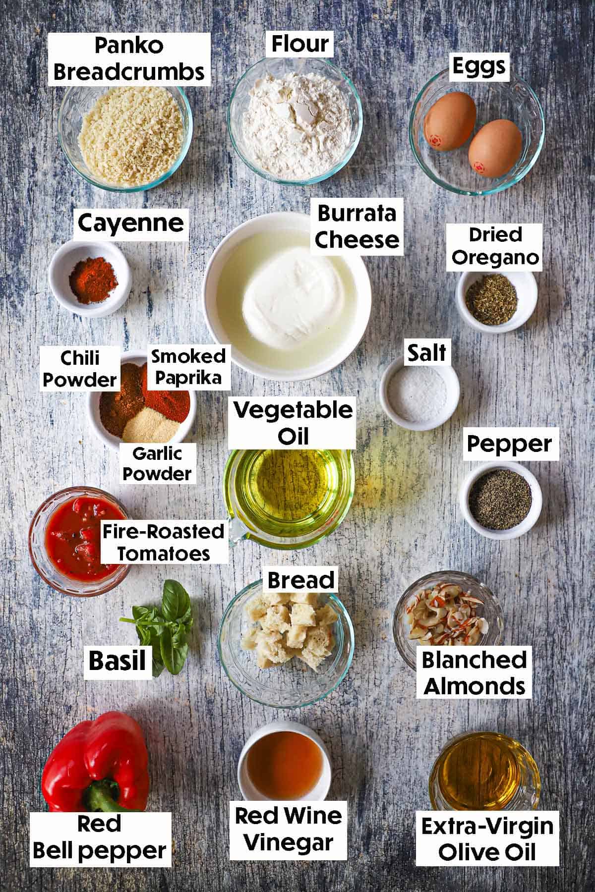An arrangement of ingredients for Crispy Fried Burrata with Smokey Romesco Sauce including red bell pepper, diced tomatoes, oil, burrata cheese, flour, eggs, breadcrumbs, and seasonings.
