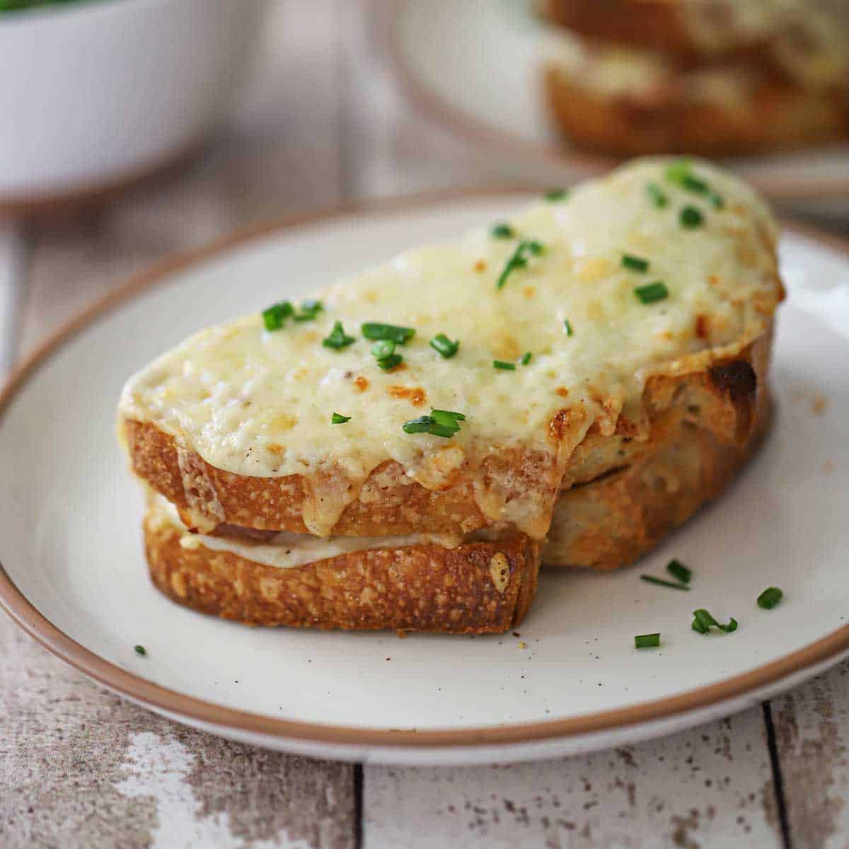 A close-up view of a freshly made Essential Croque Monsieur and is garnished with a sprinkling of snipped chives.