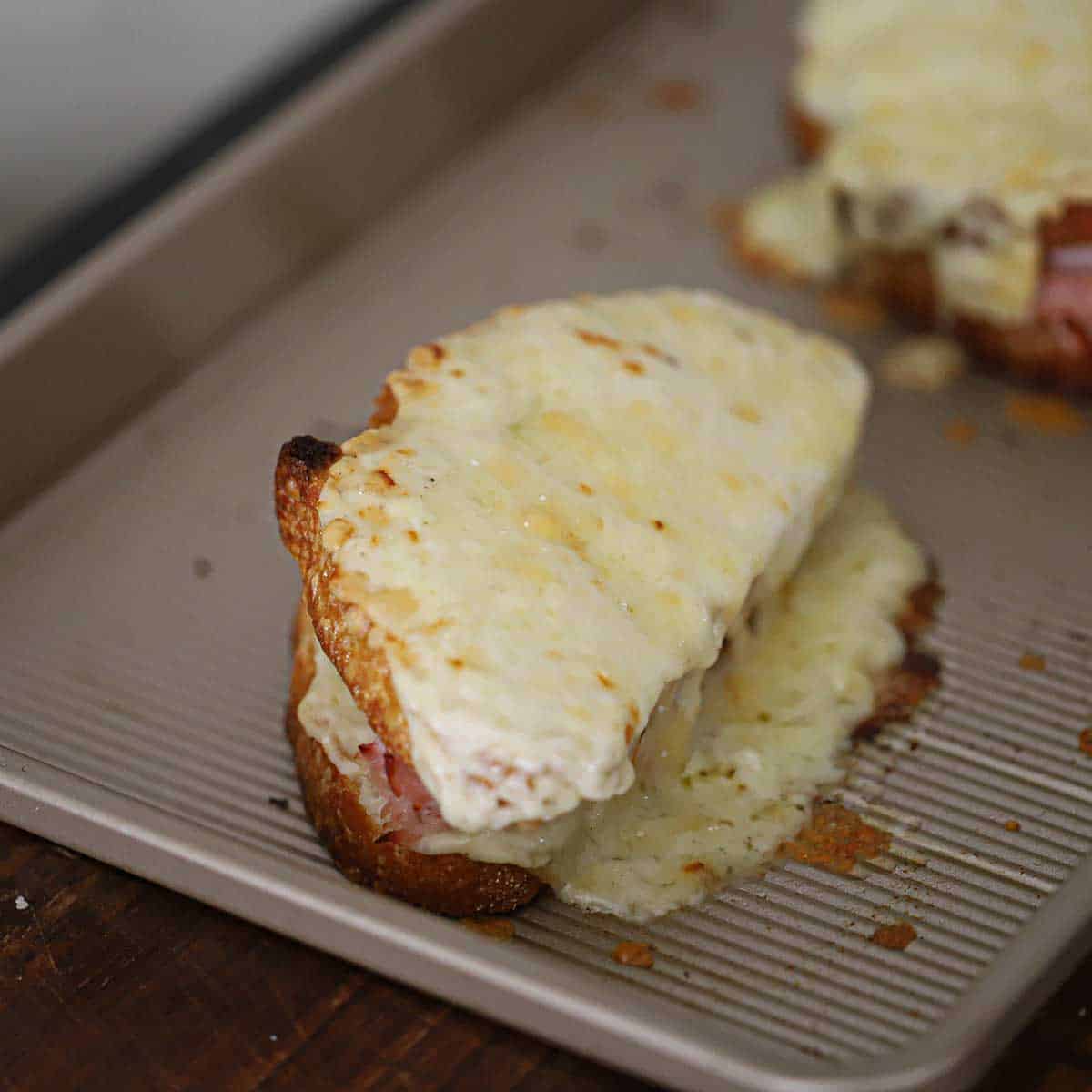 A close-up view of a Croque Monsieur sandwich that is covered with melted Gruyere cheese and is fresh out of the oven.