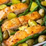 A close-up view of sheet pan honey garlic salmon and roasted veggies next to a colorful linen.