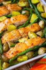 A close-up view of sheet pan honey garlic salmon and roasted veggies next to a colorful linen.